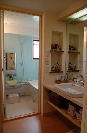 洗面所：クスの無垢板で作ったオリジナルの洗面カウンター。鏡と照明は再利用したＥＣＯリフォーム。